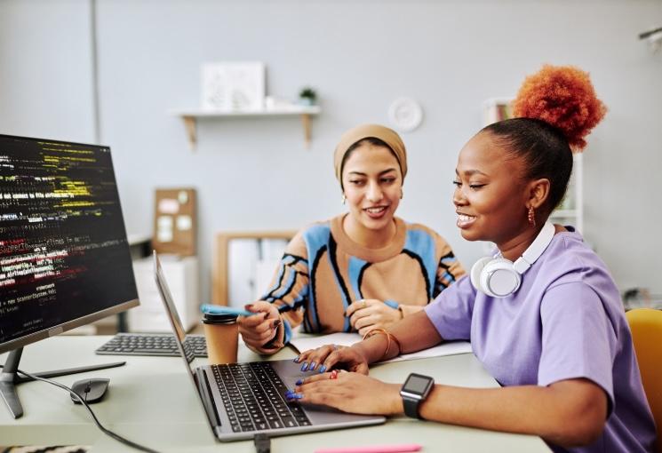 Two employees gathered round a laptop smiling together