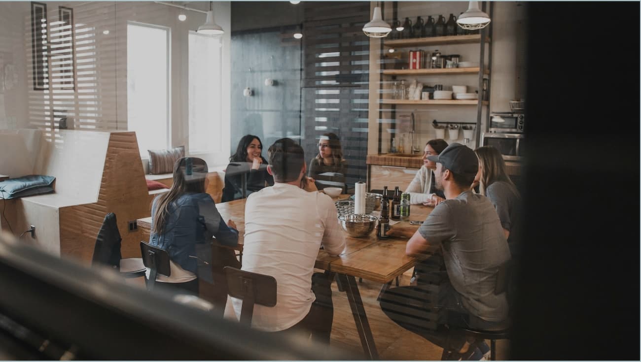 People sat around a table in a stylish office kitchen setting