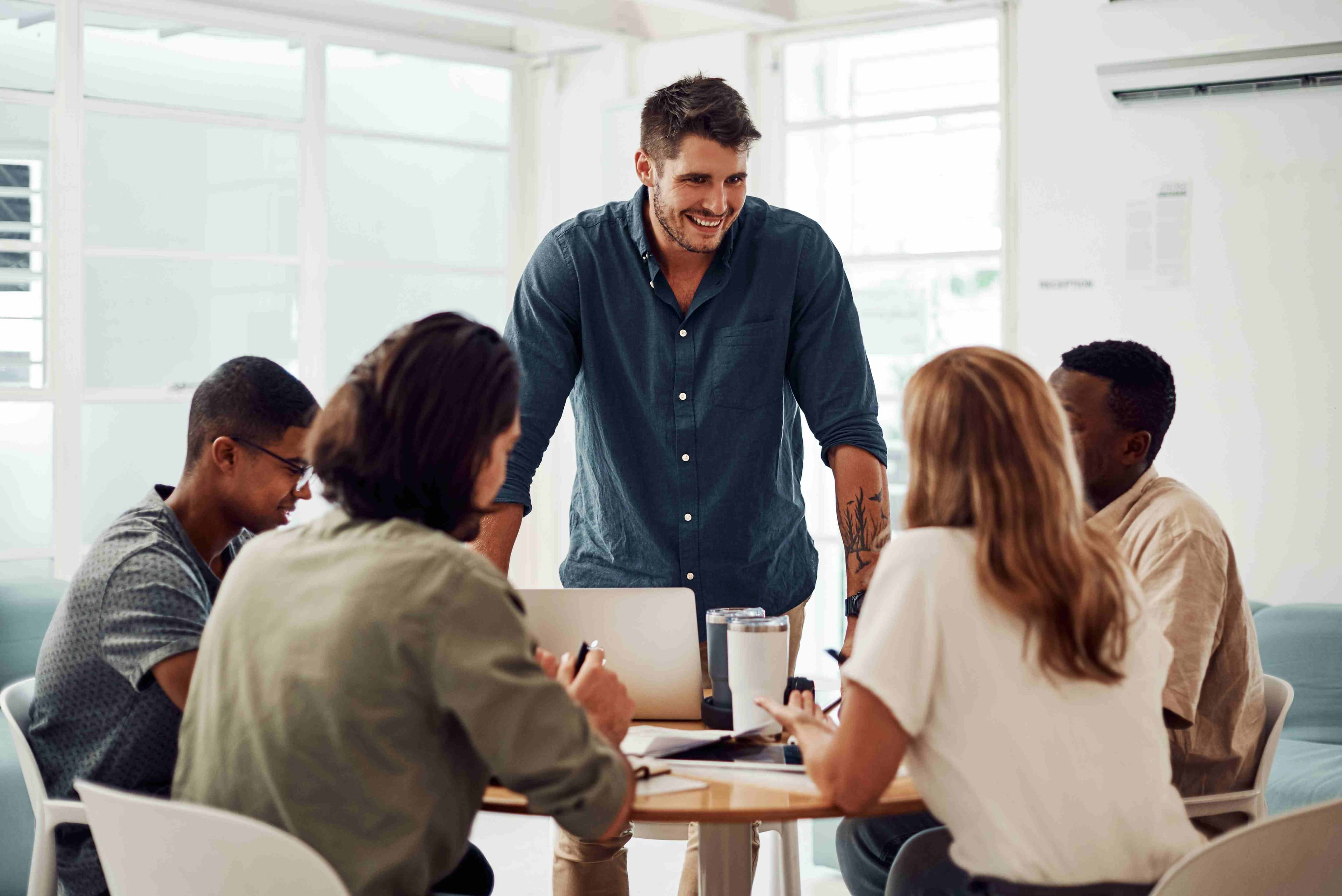 Man facing group of people presenting at a desk