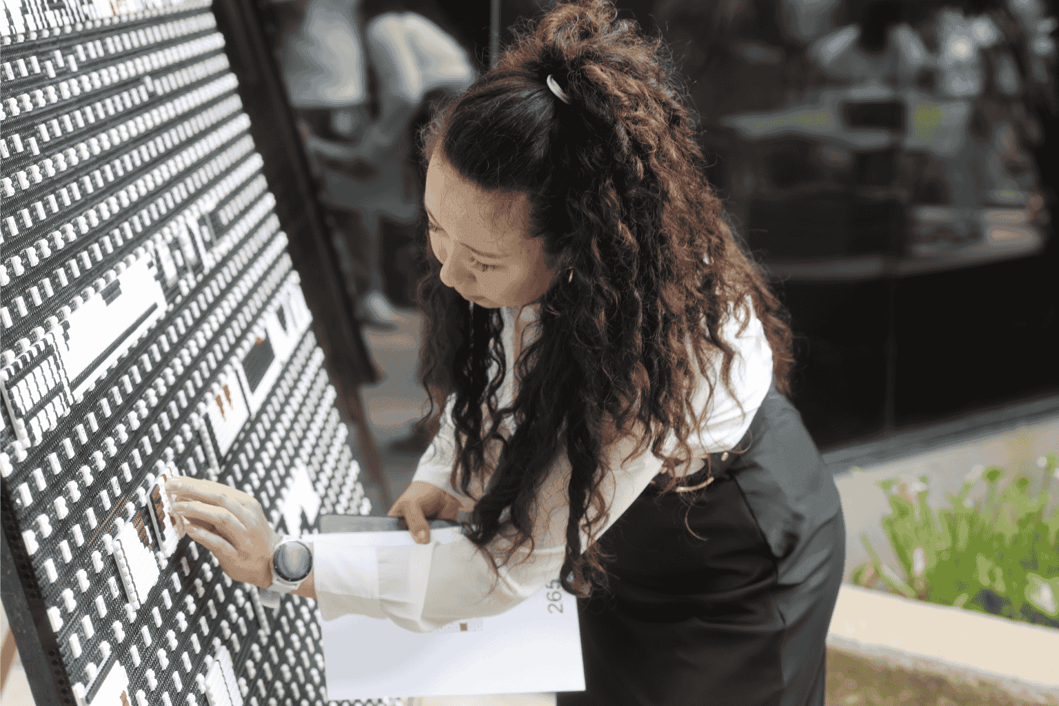 Woman standing in front of a wall, sticking items onto it