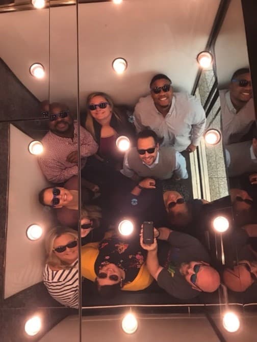 a group of colleagues looking up in an elevator mirror