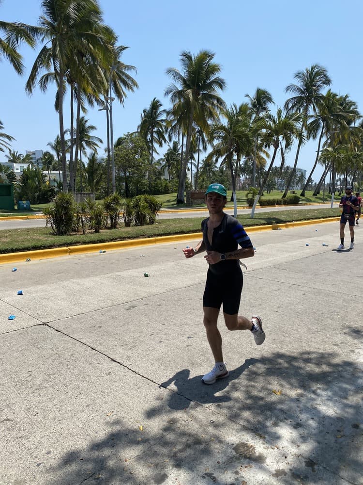 Man running on road with palm trees and blue sky behind