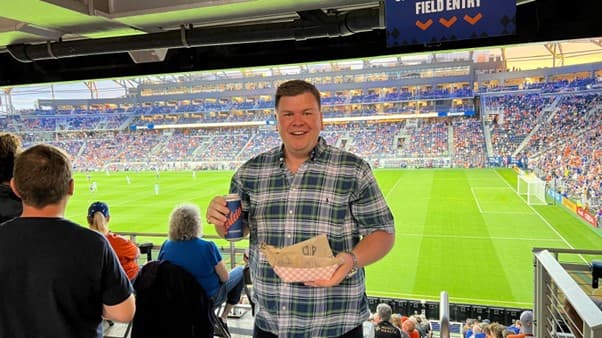 colleague at a sporting event smiling and holding food