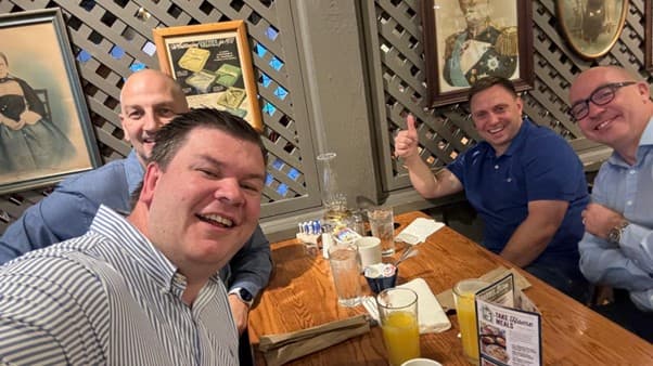 male colleagues sitting at a table smiling