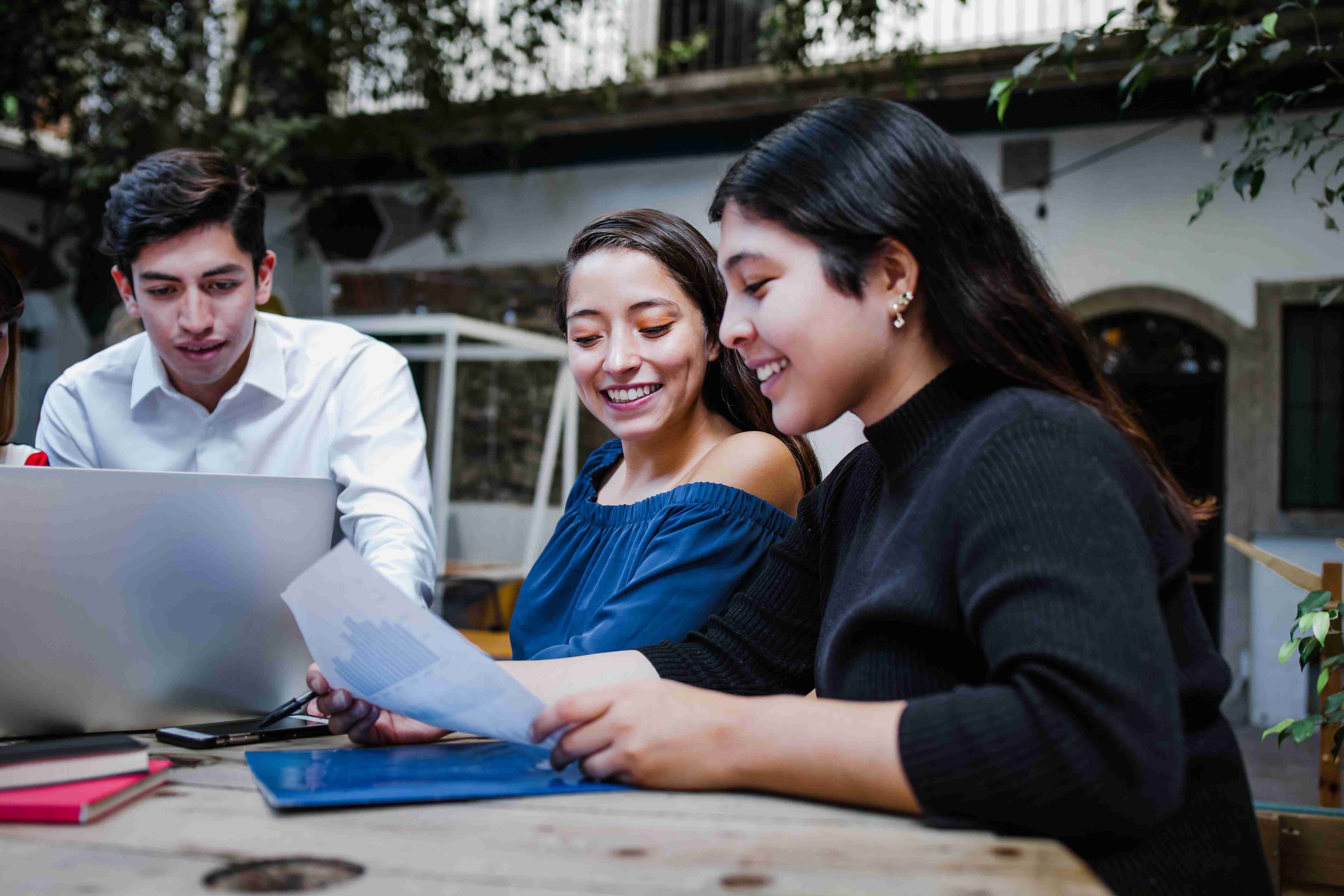 3 young people sat around a table working